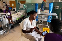 Children's Surgical Hospital, sub-intensive unit. Social worker Namangale Jane Majale talks to Blessing Nayiga's cousin, F, 4 and a half years old, who underwent surgery 2 days ago for a teratoma on an ovary. Blessing is the youngest of 3 sisters. Her mother is a waitress in Saudi Arabia, her father raises chickens. Her cousin Namukose assists her in the hospital because her father takes care of her sisters. Namukose, 18, did not finish the 6th grade of primary school interrupted by Covid. She doesn't have the money to continue studying. Entebbe, Uganda, 2023