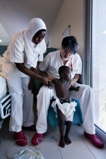 Children's Surgical Hospital, sub-intensive unit. Obanga Kene Regan, M, 3 years and 2 months, operated for bladder exstrophy, is no longer in traction. With Alberto Carreno, physiotherapist. Entebbe, Uganda, 2023