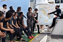 On board the EMERGENCY SAR Life Support ship, Commander Laura Pinasco announces to the 65 survivors the assigned POS: the port of Ortona. On her left, cultural mediator Mariam Bouteraa and on her right, Dr. Eleonora Padua.